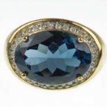 A 9ct gold diamond and blue stone ring with oval cut claw set blue stone in a border of tiny diamond