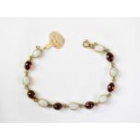 A 9ct gold bracelet set with alternating cabochon red stones and opals, stamped 375, approx. 9.2g.