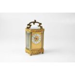 A brass cased carriage clock with Rococo scroll border, the ivorine dial set with Roman numerals,