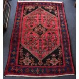 A vintage 20th century Afghan rug with a central red ground lozenge with floral decoration, black