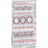 A Far Eastern woven saddle rug with geometric patterns on a grey and white ground, 135 x 55cm.