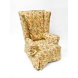 An early 20th century wing back armchair with floral upholstery, raised on cabriole legs to pad