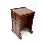 An Edwardian oak school desk with lift-up top, panelled sides and cupboard door to front, all to