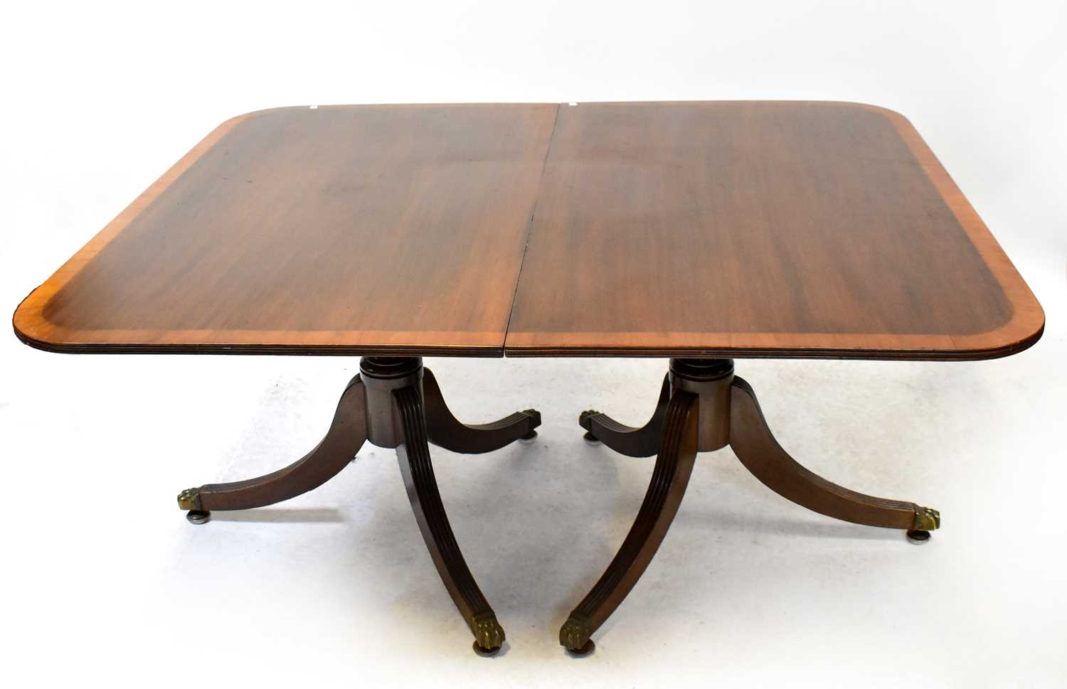 A 19th century crossbanded mahogany extending dining table on three pedestal legs, with three