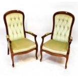 A pair of reproduction mahogany framed open arm elbow chairs with upholstered seat and button