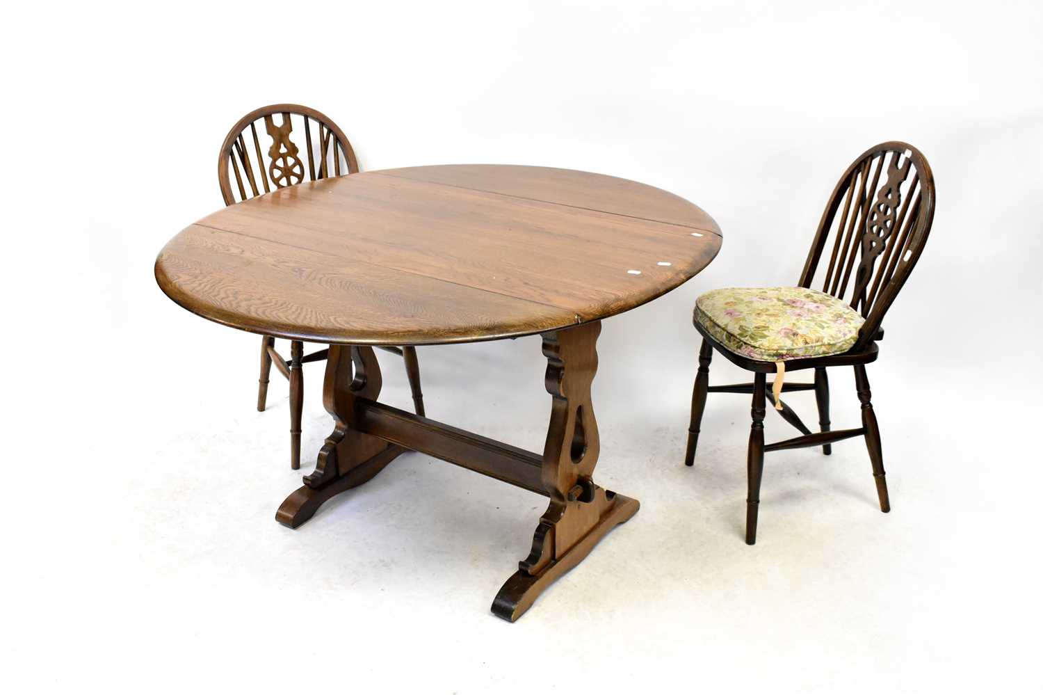 A mid-20th century oak priory-style draw-leaf dining table with shaped slab ends, cross stretcher