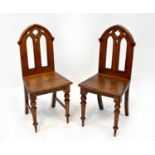 A pair of oak hall chairs, the arched tops above pierced backs, solid seats and turned stretchered