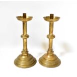 A pair of 19th century ecclesiastical brass candlesticks with flared bowls and knopped stems, on