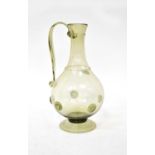 A 19th century pale green glass jug with raised roundels to stepped circular base, height 26.5cm (