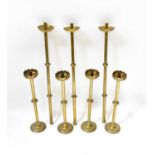 Four matching late 19th century brass ecclesiastical candlesticks with knopped stems, on domed feet,