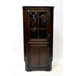 An Old Charm oak floor standing corner cupboard, with glazed cupboard door above cupboard door.