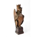 A wooden carved mythical winged dragon holding shield with cross of St George, on stepped base,