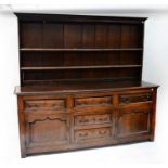 A George III oak dresser with enclosed plate rack above five drawers and two fielded and panelled
