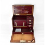 An early 20th century oak desktop stationery box with lift-up lid and fold-down front, with four-