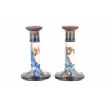 WALTER MOORCROFT; a pair of tulip pattern candlesticks, height 21cm, diameter of base 12cm, with