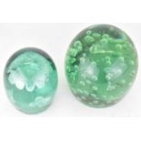 Two Victorian green glass dump paperweights, the largest example with floating bubbles, 13 x 10.5cm,