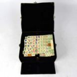 An early 20th century leather cased Mah-Jong set with bone-faced bamboo-backed tiles, each tile