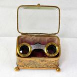 A pair of opera glasses with snakeskin covers, housed within a small gilt brass jewellery casket,