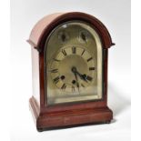 An early 20th century mahogany arched top mantel clock, the silvered dial set with Roman numerals,