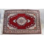 A red ground carpet with central medallion within floral border, 230 x 150cm.