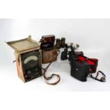 A group of vintage binoculars and a voltmeter.