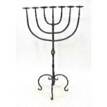 A large wrought iron pricket candlestick with pierced column and four scrolling supports, height