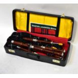 A contemporary cased set of turned wooden bagpipes.