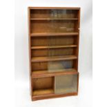 MINTY; a four-tier oak bookcase with glazed sliding cupboard doors, 165 x 89 x 29cm.