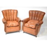 A pair of Art Deco style tan leather upholstered armchairs on mahogany outswept feet (2).