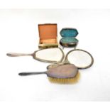 A George V hallmarked silver part dressing table set comprising hand mirror, hairbrush and small