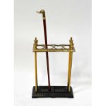 A brass umbrella and stick stand with four compartments, on a metal base with recessed drip trays,