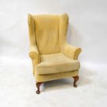 A 1930s oak framed wing back armchair upholstered in a cream woven fabric, on cabriole legs.