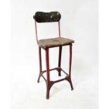 A 1920s red painted metal framed workshop back stool with wooden saddle seat, height 90cm.