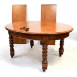 A circular oak dining table with two extra leaves and wind-out handle, to barleytwist legs, closed