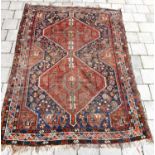 A late 19th/early 20th century Afghan rug, with two red medallions within a blue border, on a red