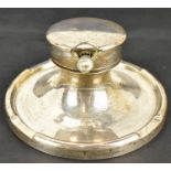 A George V hallmarked silver capstan inkwell, the lift-up lid with pocket watch style clock, the