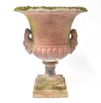 A contemporary reconstituted garden urn with figurehead handles, raised on a square section base,