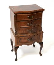 A reproduction mahogany crossbanded serpentine-fronted four-drawer bedside chest, raised on carved
