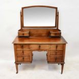 An Edwardian mahogany kneehole dressing chest, the arched bevelled plate above a pair of short