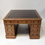 An early 20th century mahogany partners' desk of small proportions, with gilt tooled oxblood leather