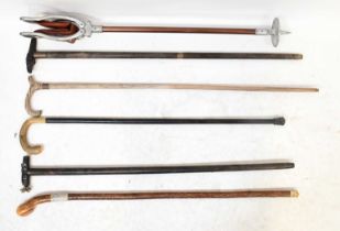 A small collection of walking sticks, including two examples with novelty tops, one in the form of a