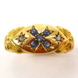 An 18ct gold ring with cross-shaped pattern, incorporating four small blue stones, flanked by two