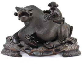 A late 19th/early 20th century carved wooden figure depicting a man riding an ox, unmarked, height