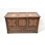 An early 20th century oak triple panelled coffer with carved detail to the lid, raised on squat