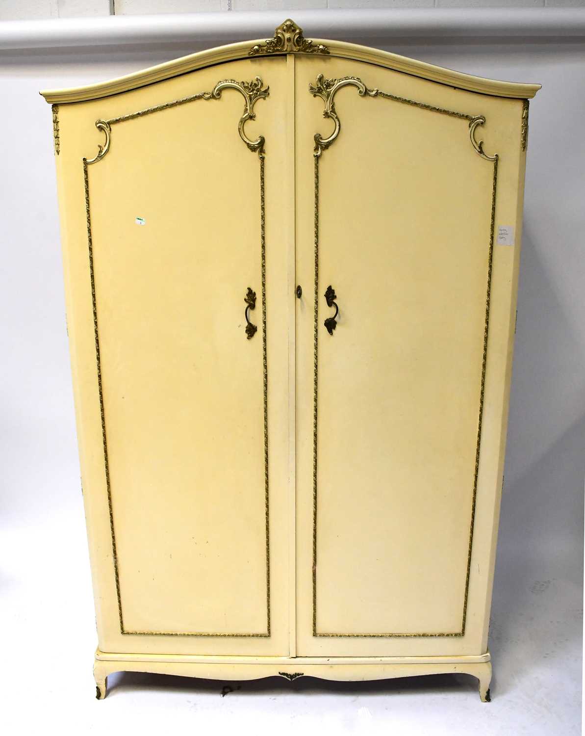 A five-piece gilt-heightened cream bedroom suite comprising two double wardrobes, a chest of five