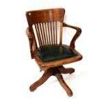 A 1920s mahogany revolving open arm office chair, with green leather studded base and slatted