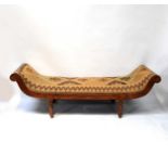 A modern reproduction mahogany day bed with carpet-style textile covering, raised on turned