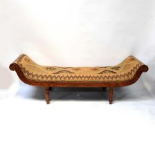 A modern reproduction mahogany day bed with carpet-style textile covering, raised on turned