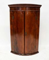 A mahogany line inlaid bow-fronted two-door wall-hanging corner cupboard with exposed brass