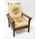 A 1930s oak adjustable open arm elbow chair with ladder back and loose tapestry-style cushions,